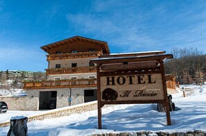 A wooden sign for a hotel with a stone building in the background.