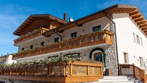 A two-story building with wooden balconies, stone facade, and a clear blue sky. - Boutique Hotel Il Riccio (Roccaraso)
