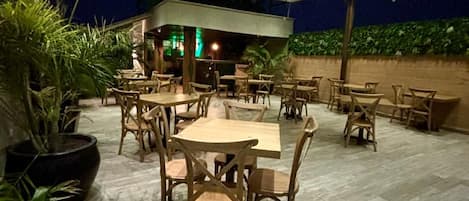 An indoor dining area with multiple tables and chairs, a bar area, and potted plants.