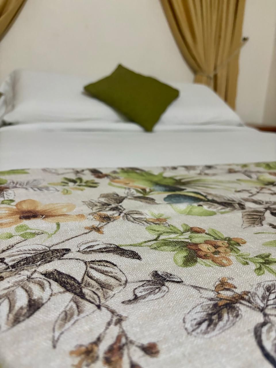 A bed with a floral-patterned bedspread and a green pillow.