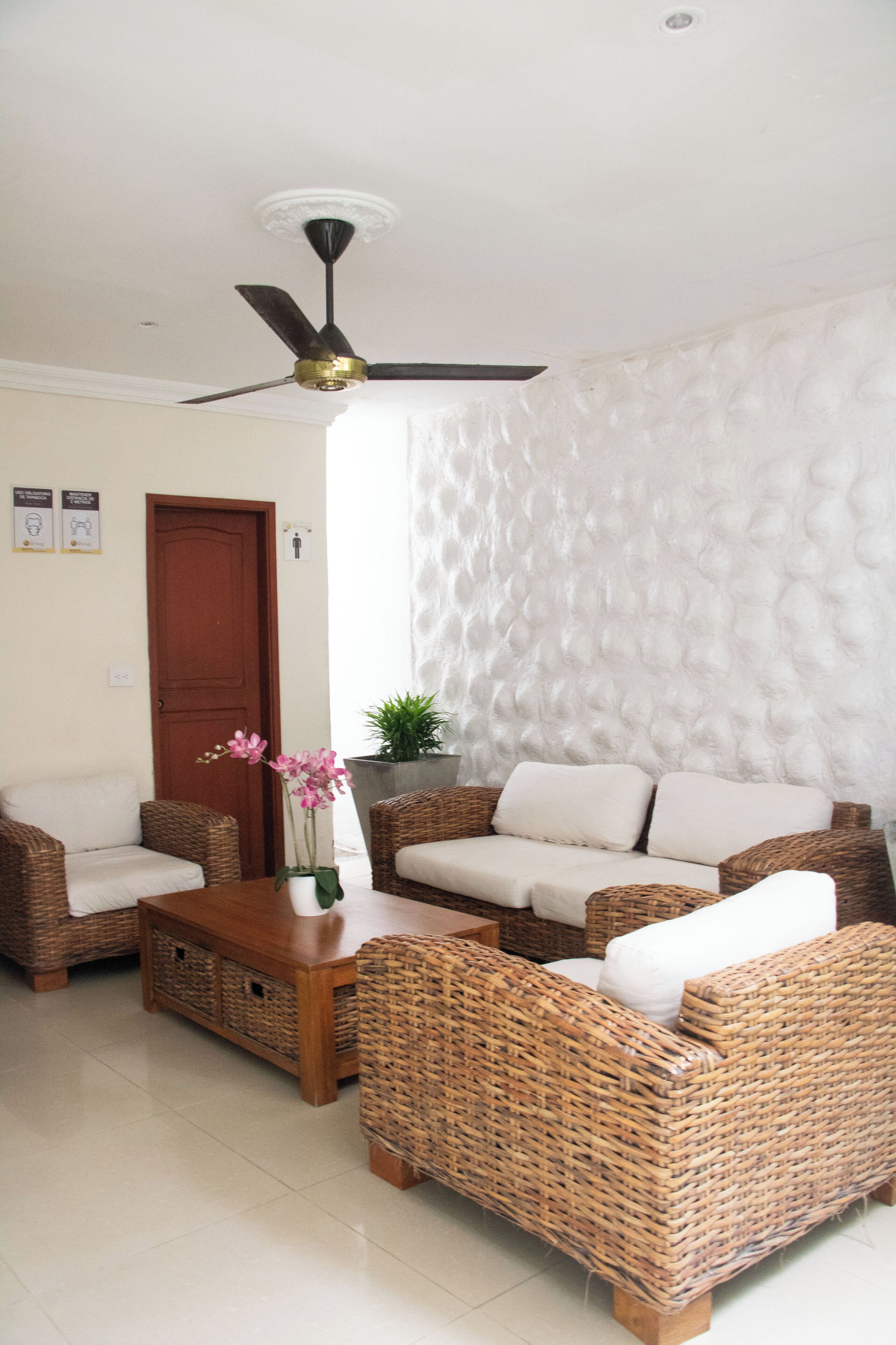 A living room with wicker furniture, a ceiling fan, and a textured wall.