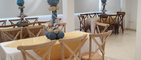 Une pièce avec des chaises et des tables en bois, dont certaines sont recouvertes de nappes jaunes.