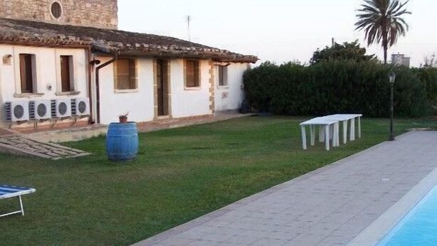 A poolside area with a tiled deck, a white table, and a blue barrel. - Aranceto (Syracuse)