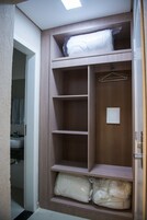 Un armario amplio con varias repisas, una barra para colgar ropa y una puerta con interruptor de luz.