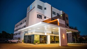 A modern hotel with a prominent 'Aquarius Express' sign, a covered entrance, and a parking area with a white vehicle. - Iguassu Express Hotel (Foz do Iguaçu)