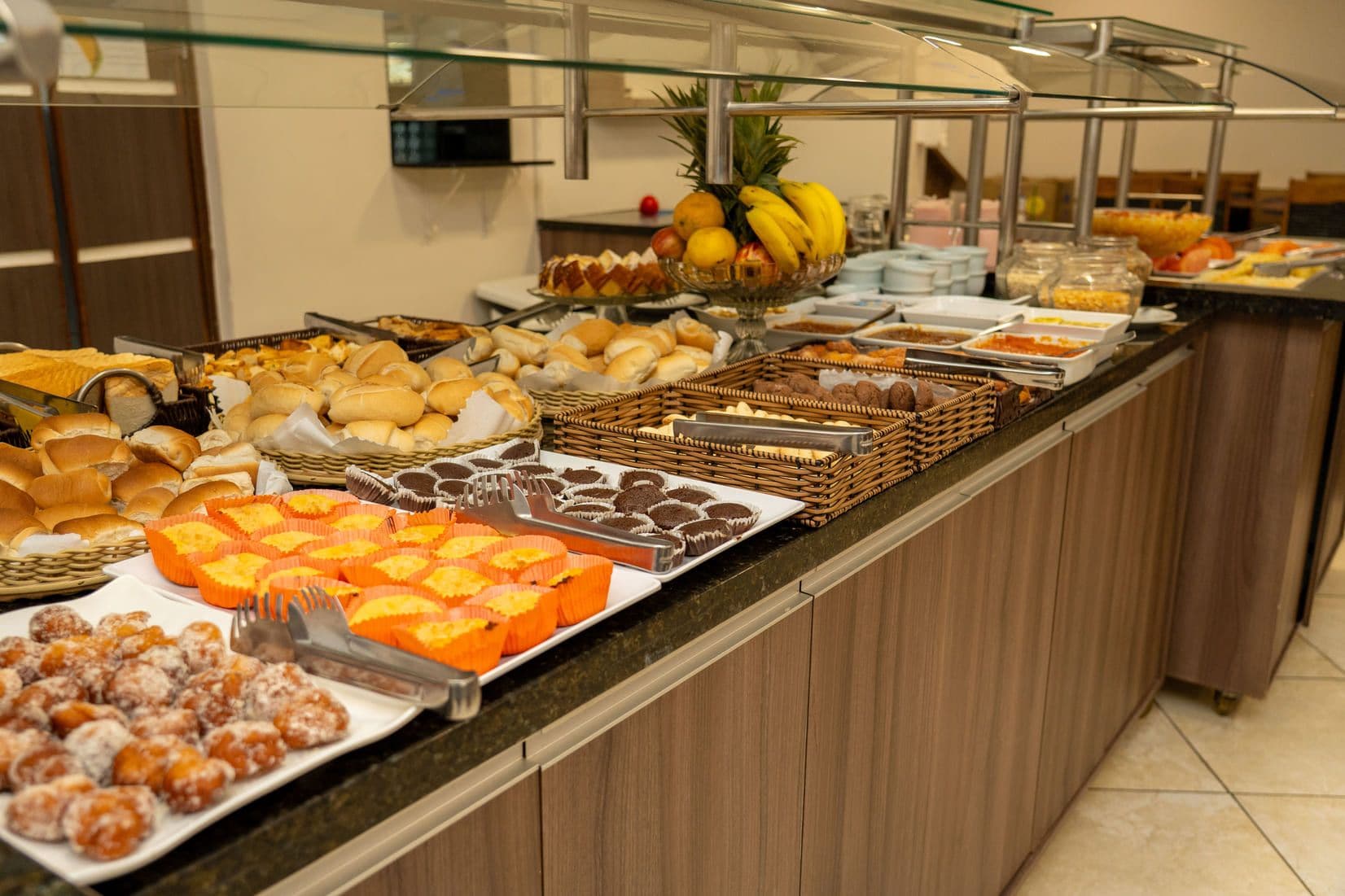 Un buffet proposant une variété d’aliments, notamment des pâtisseries, des fruits et du pain.