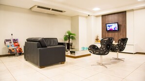 A modern waiting area with a leather sofa, a glass coffee table, and contemporary chairs. - Iguassu Express Hotel (Foz do Iguaçu)