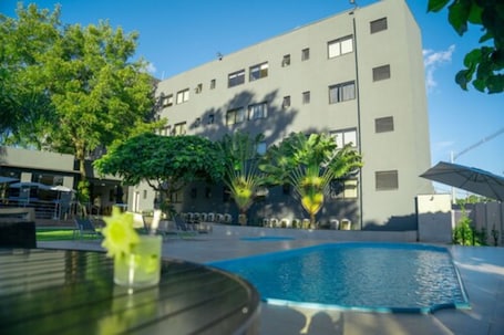 Una piscina al aire libre, sombrillas, sillones reclinables de piscina