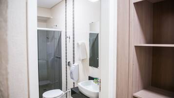 Uma casa de banho moderna com sanita, lavatório e cabine de duche em vidro.