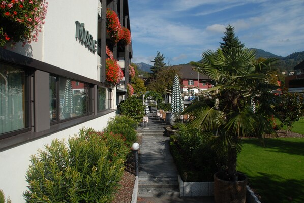 A hotel with a pathway leading to the entrance, surrounded by greenery and a mountain backdrop.