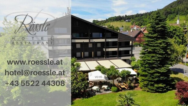 A hotel with a modern black facade, outdoor seating area, and a view of a green landscape. - Hotel Rössle (Roethis)