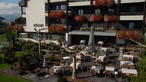 A hotel with outdoor seating, flower boxes on balconies, and a well-maintained garden. - Hotel Rössle (Roethis)