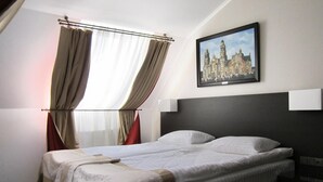 A hotel room with a bed, curtains, a framed picture on the wall, and a bedside table. - Optima Collection Kharkiv Hotel (Kharkiv)