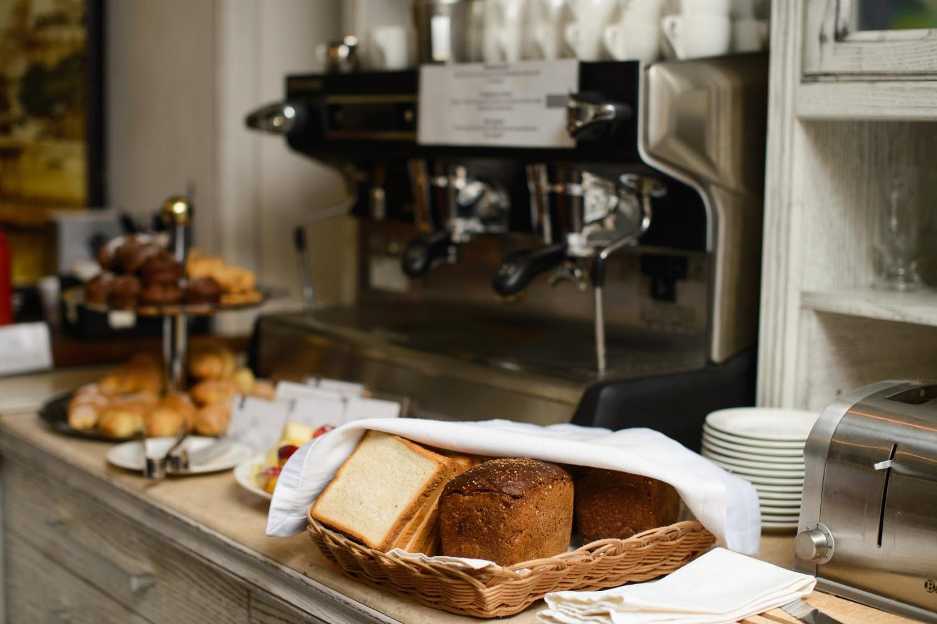 En morgenmadsbuffet med brød, kager og en kaffemaskine.