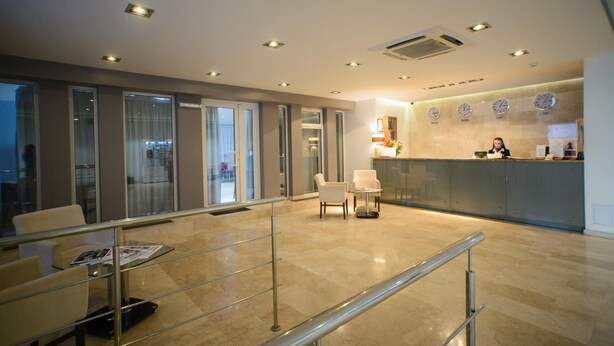 A modern hotel lobby with a reception desk, seating area, and glass doors leading to a hallway. - Optima Collection Kharkiv Hotel (Kharkiv)
