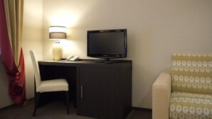 A hotel room with a desk, a television, a lamp, a chair, and a sofa. - Optima Collection Kharkiv Hotel (Kharkiv)
