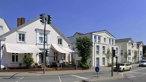 Vista de la calle con edificios residenciales, un semáforo y un automóvil.
