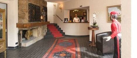 A lobby with a stone wall, a red carpet, and a receptionist desk.