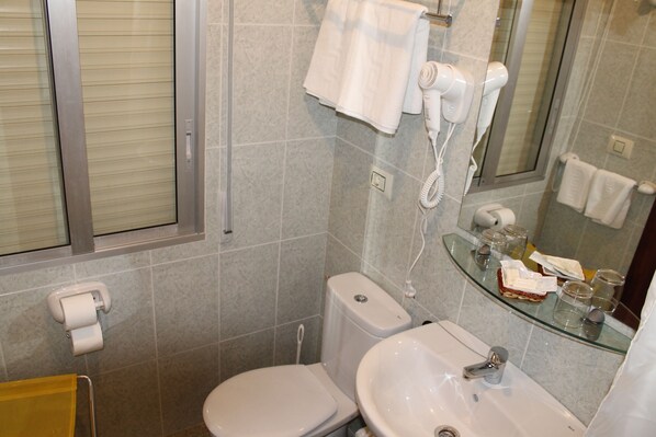 A bathroom with a toilet, sink, and a glass shower enclosure. - Hotel Foxos (Sanxenxo)