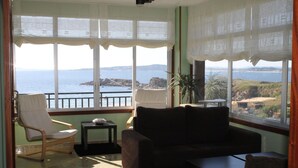 Una habitación con vista al mar, un sofá, una silla y una mesita.
