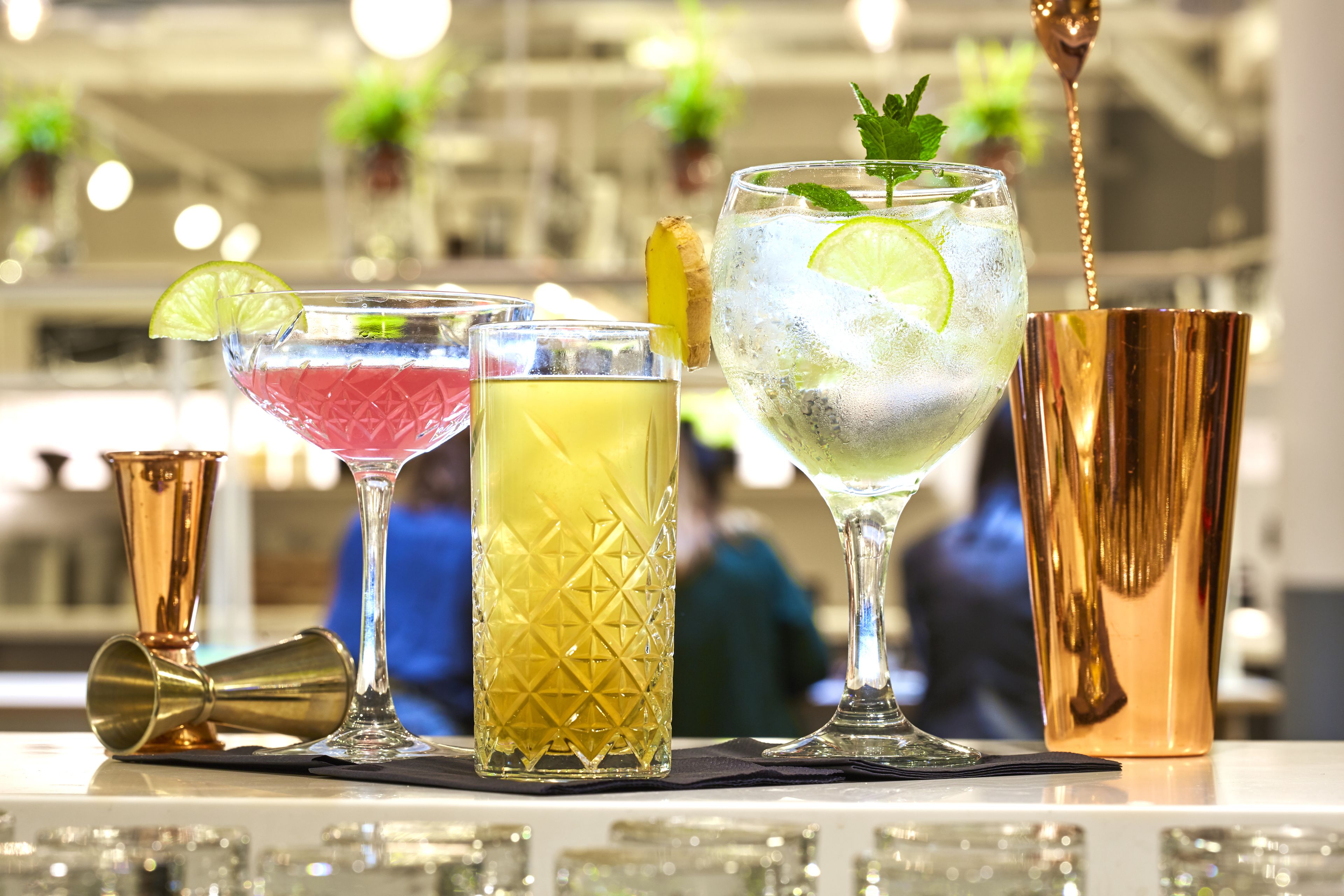 A bar area with various drinks, a copper cocktail shaker, and a gold bar tool.