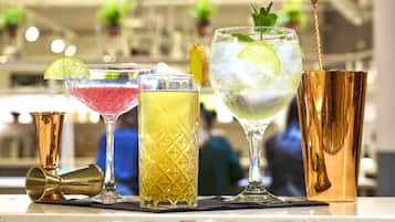 Zona de bar con diversas bebidas, un agitador para cócteles de cobre y una herramienta para barra de oro.