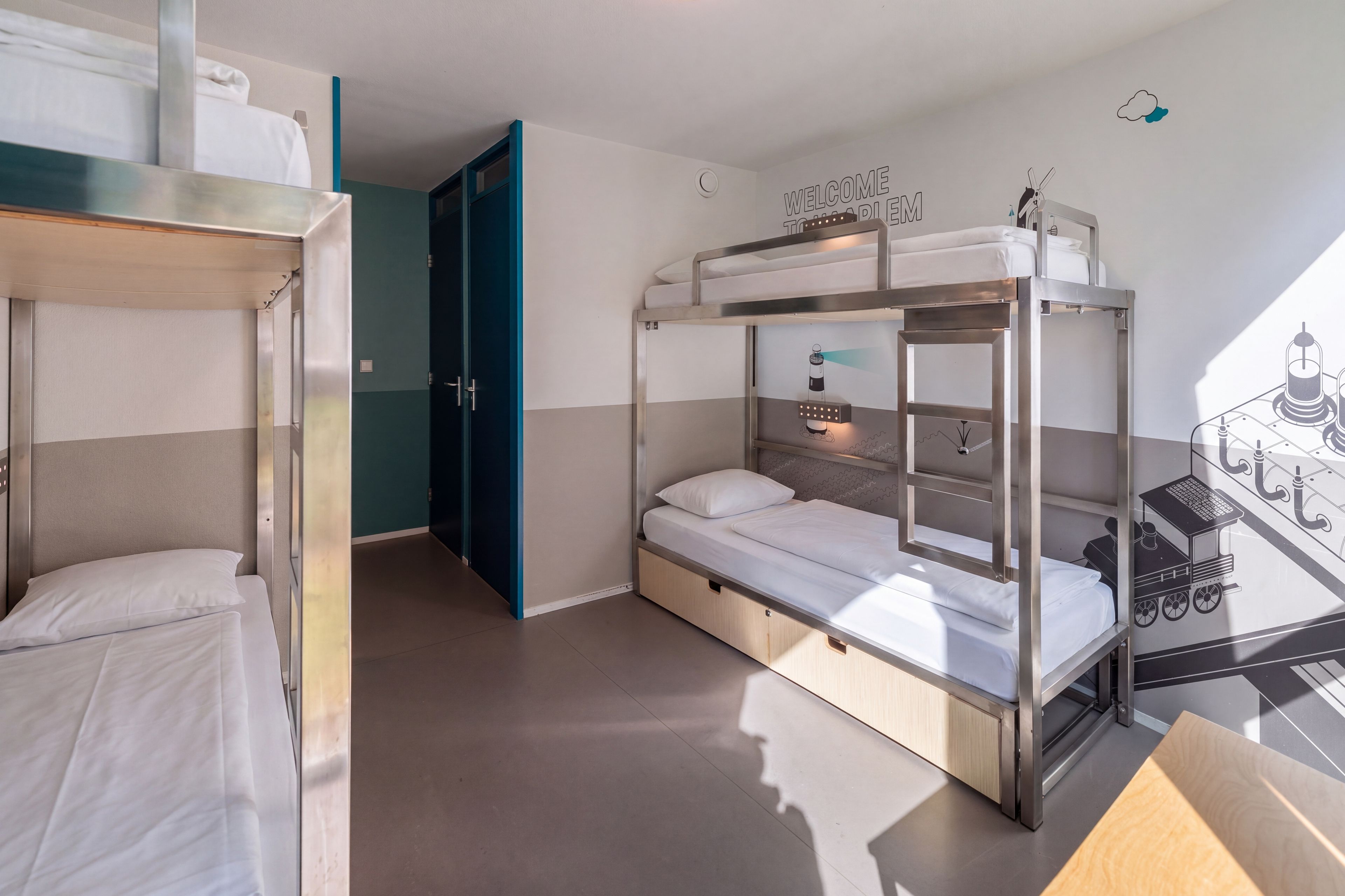 A bunk bed room with a bunk bed on the left and a single bed on the right, both with white bedding. There is a door leading to another room, and a wall with a welcome sign.