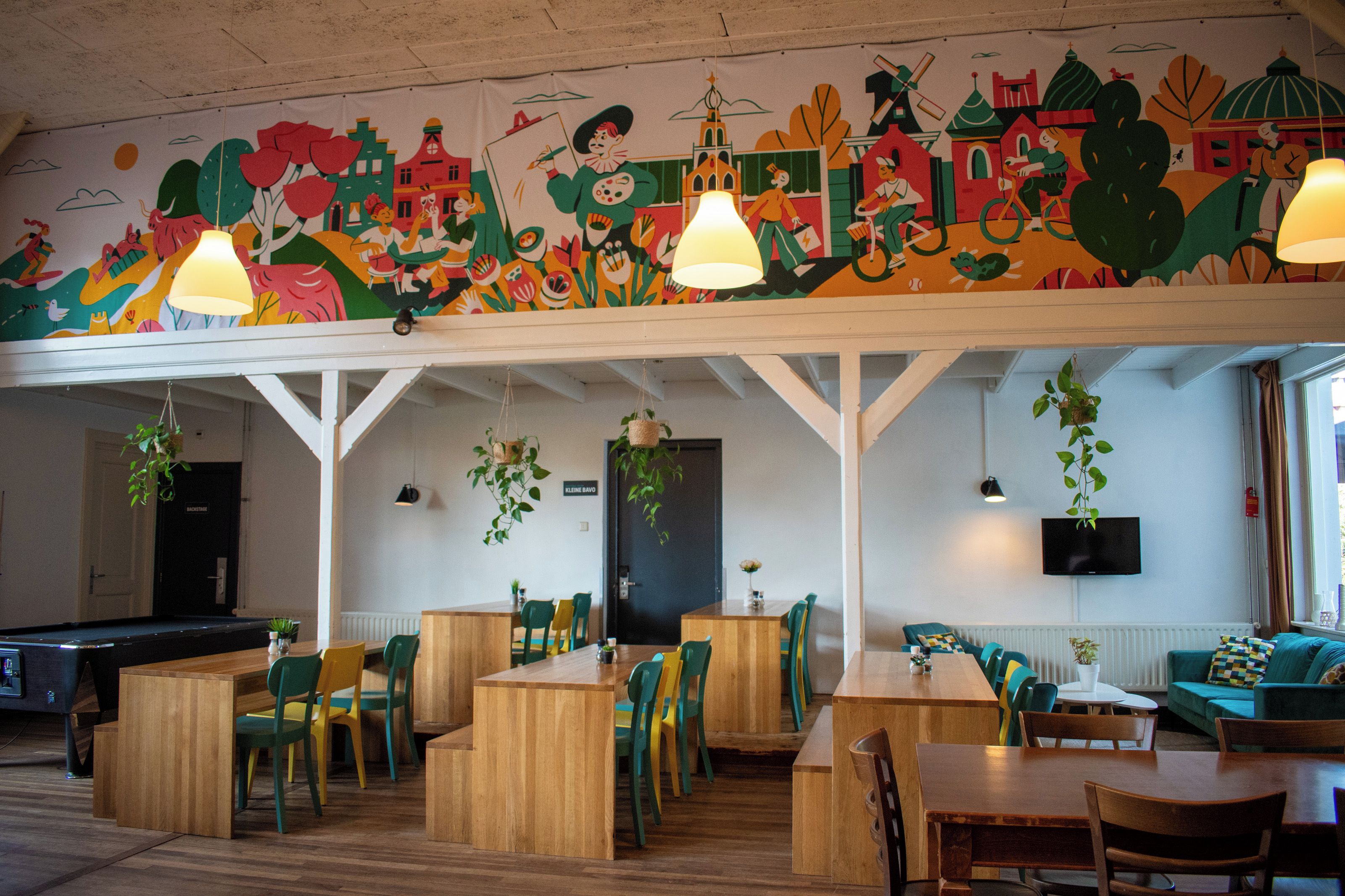 Un restaurant avec des tables et des chaises en bois, une fresque au plafond et des plantes suspendues.