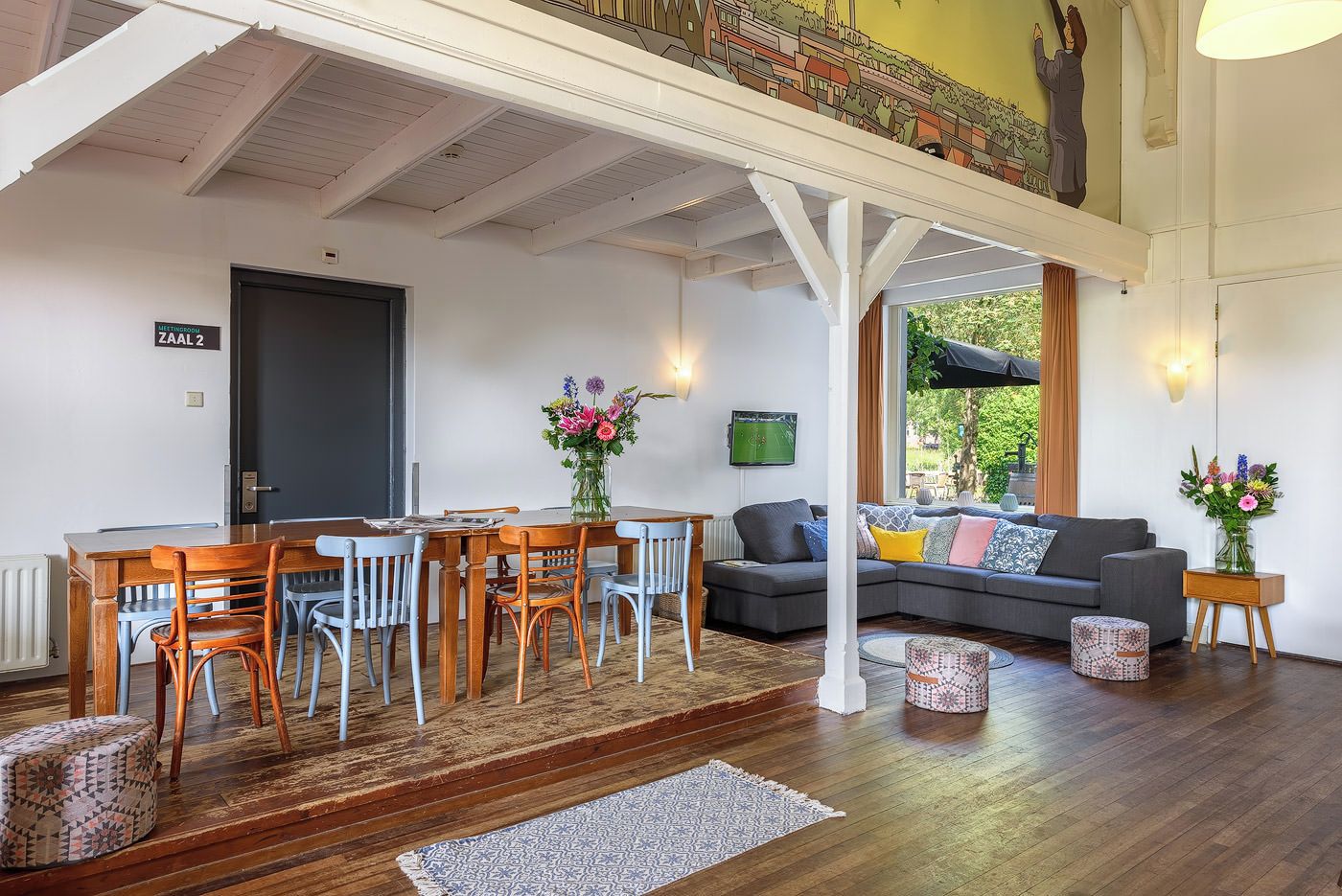 Un área de comedor con una mesa y sillas de madera, un sofá y un televisor.