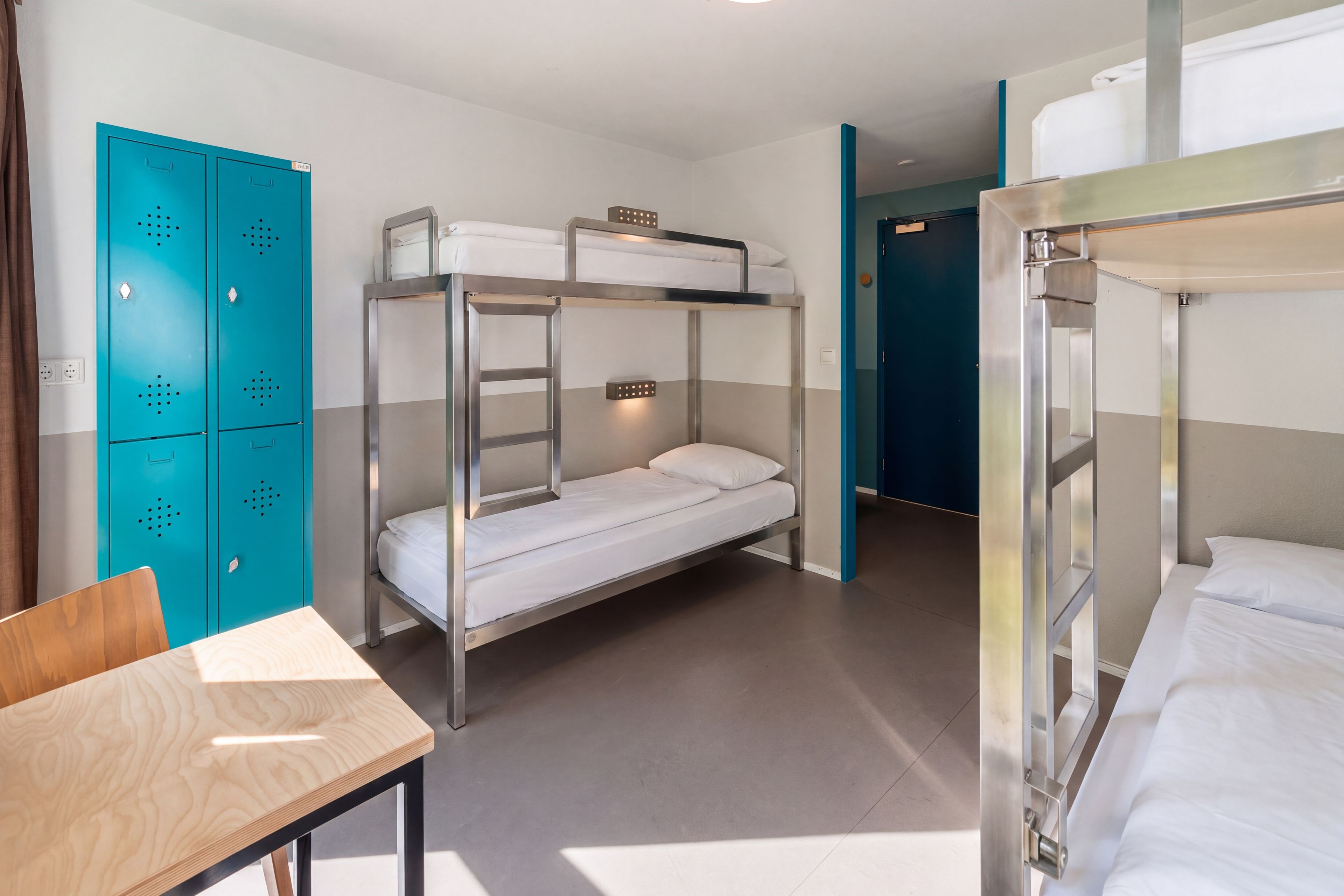 A bunk bed room with a desk and a wardrobe.