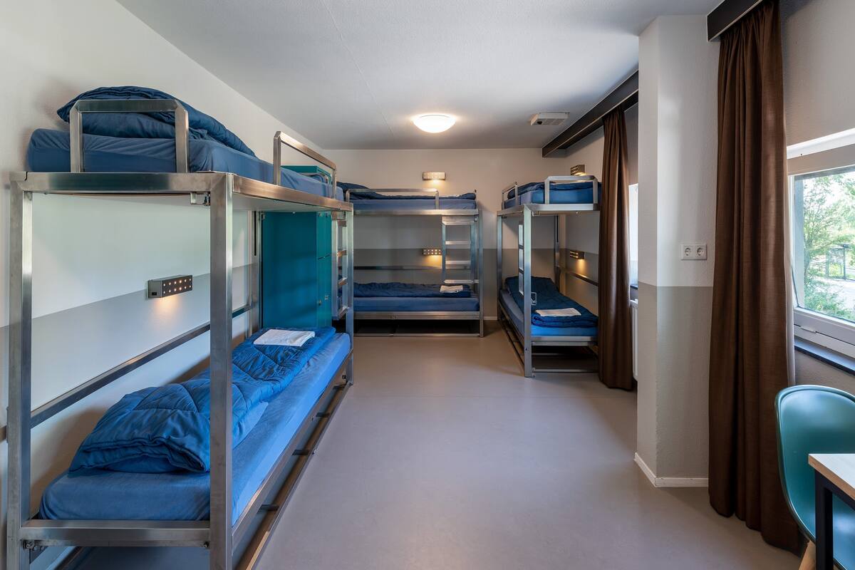 A train compartment with bunk beds, a small table, and a window with curtains.