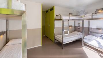 A dormitory room with bunk beds, a green door, and a welcome sign.
