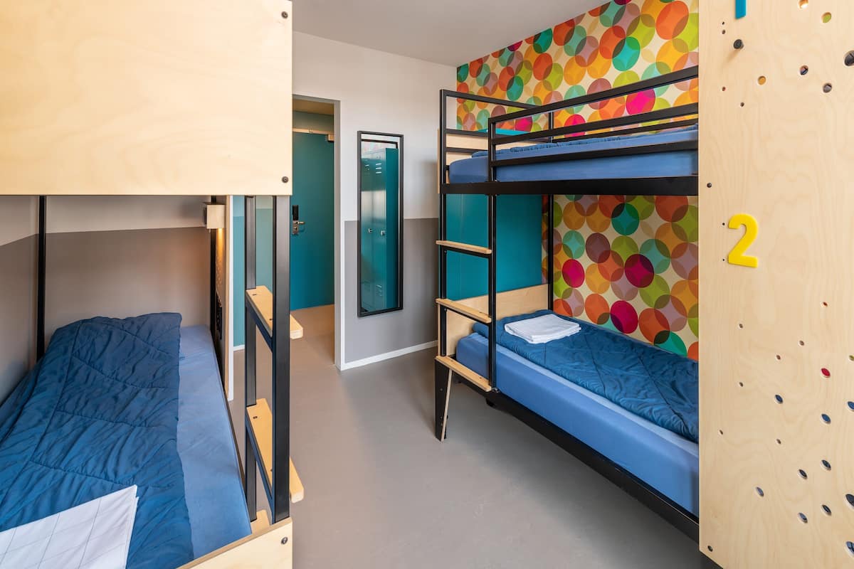 Un dormitorio con literas, una pared colorida y una puerta con un número.