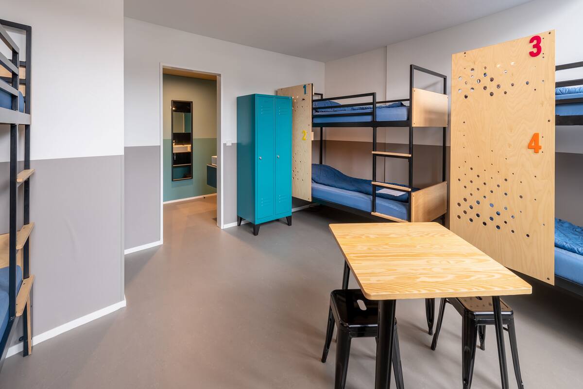 Ein Schlafsaalzimmer mit Etagenbetten, einem Schreibtisch und einem Kleiderschrank.