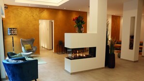 A modern living room with a fireplace, a blue armchair, and a vase with flowers.
