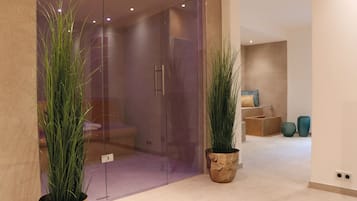 Un interior moderno con una puerta de cristal que da a una habitación con bañera, plantas en macetas y una cesta de mimbre.