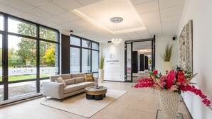 A spacious lounge with a sofa, coffee table, and a large window offering a view of the outdoors.