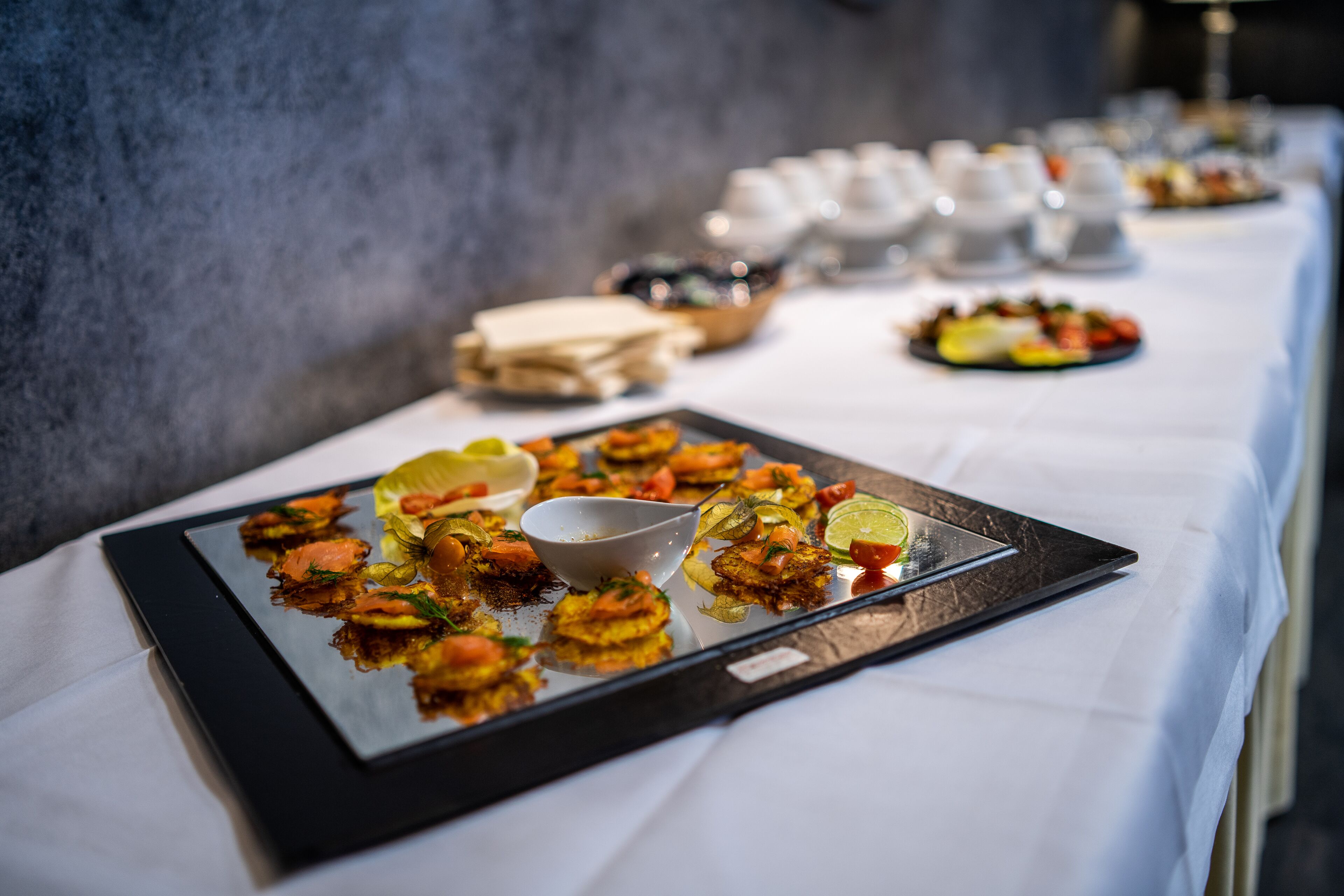 A buffet table with various dishes and a white tablecloth.