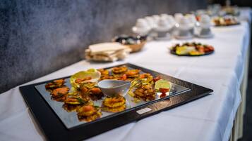 A buffet table with various dishes and a white tablecloth.