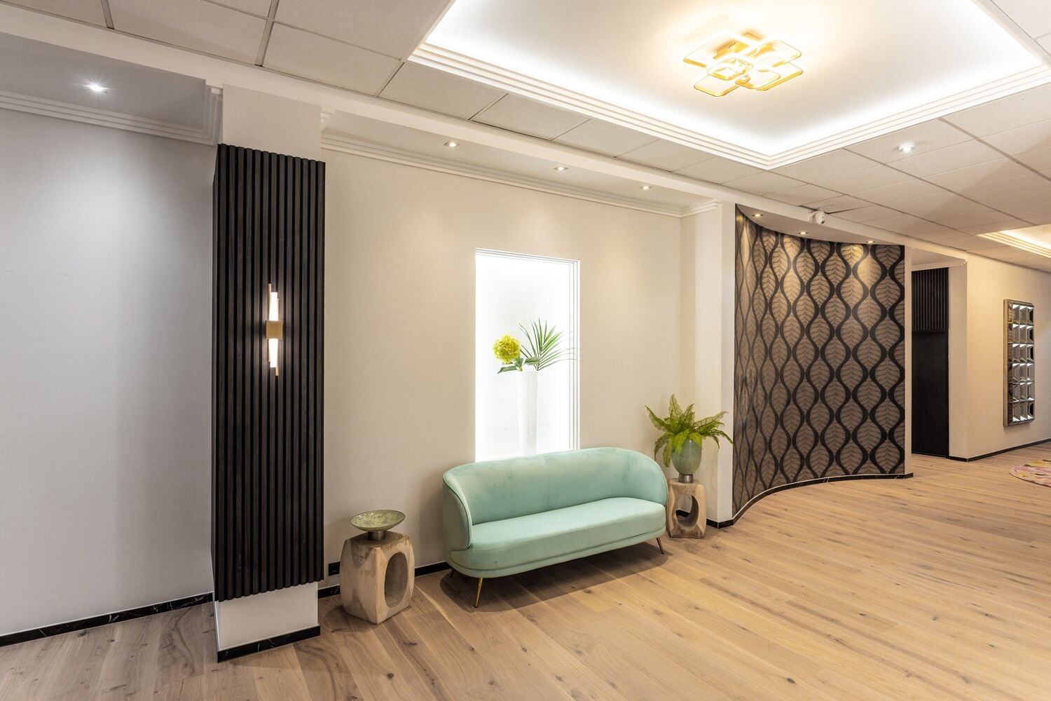 A modern interior with a light blue sofa, wooden flooring, and a decorative wall with a leaf pattern.