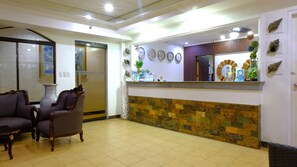 A reception area with a stone wall, a reception desk, and two armchairs.
