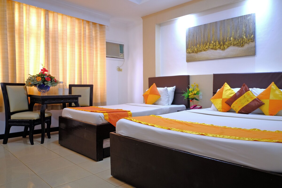 A hotel room with two beds, a desk, and a chair.