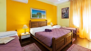 A hotel room with two single beds, a wooden headboard, a nightstand with a lamp, a wall-mounted air conditioner, and two framed pictures. - Guest House Aio Sardegna (Cagliari)