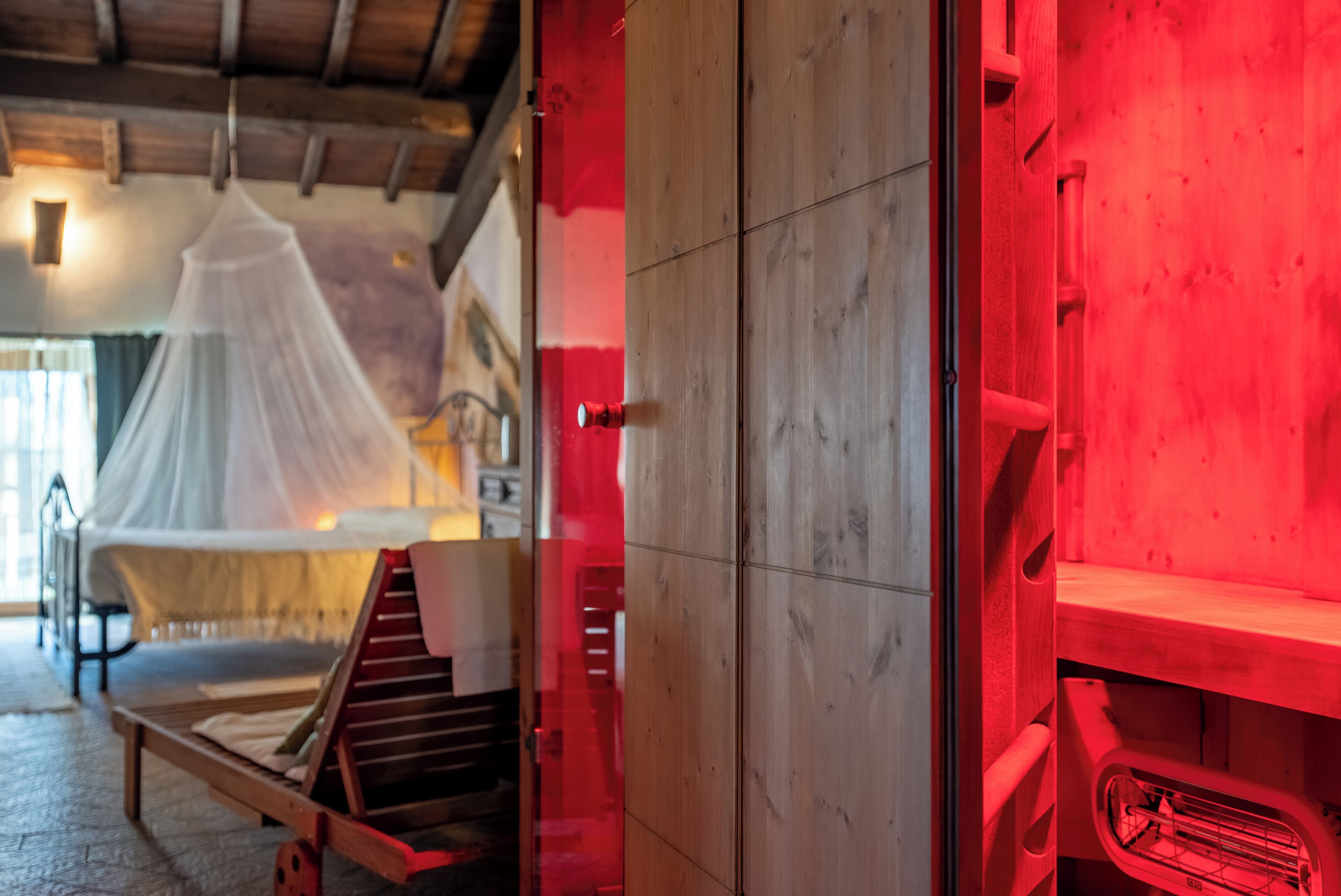 Une pièce avec un lit, un banc en bois et un mur éclairé de lumière rouge.