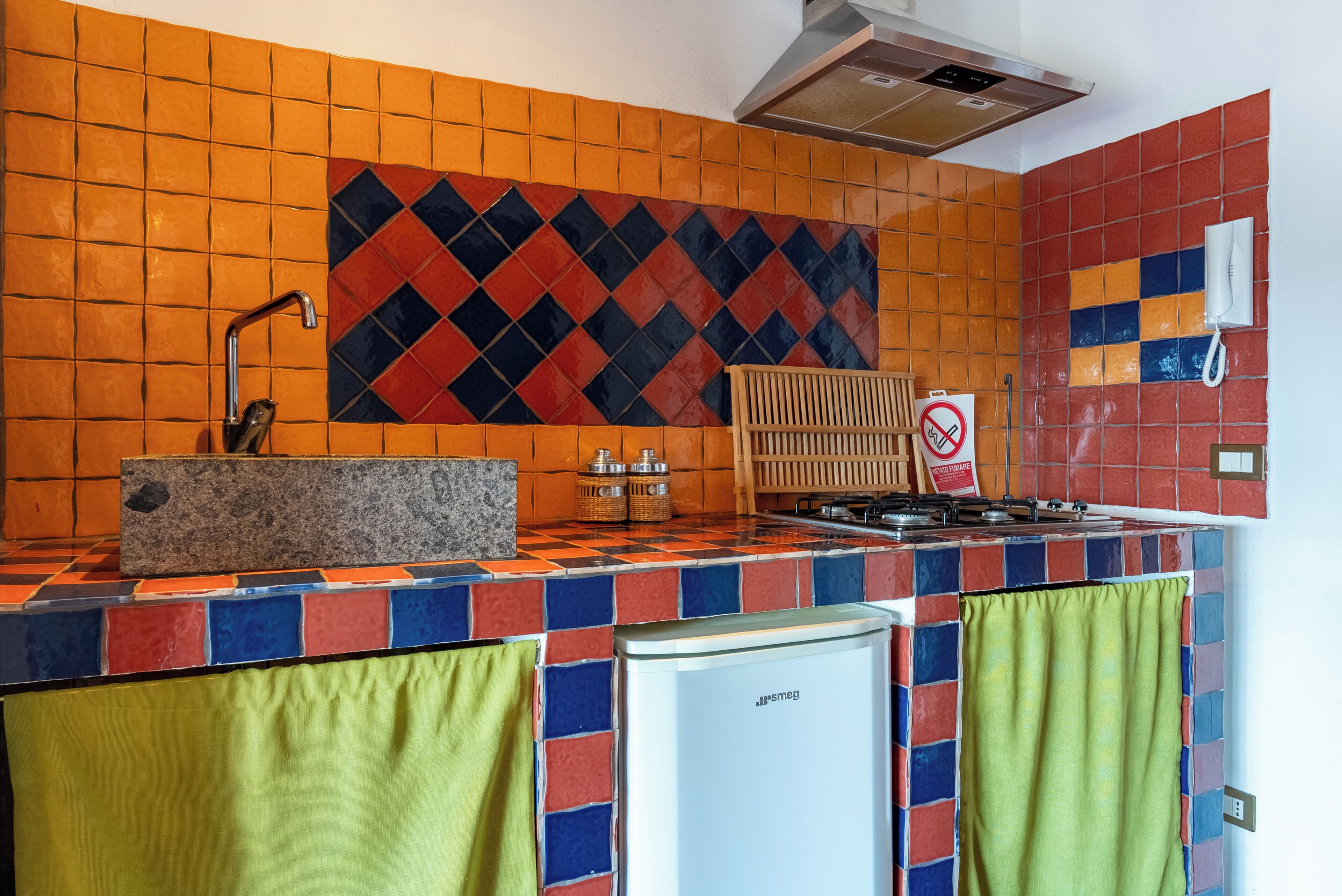 Een keuken met een betegelde spatwand, een spoelbak, een fornuis en een koelkast.