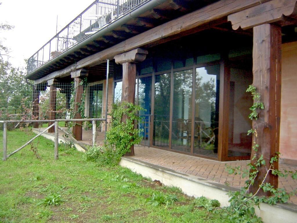 A rustic building with large windows, wooden beams, and a balcony.