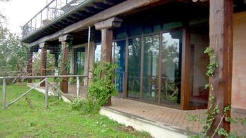 A rustic building with large windows, wooden beams, and a balcony.