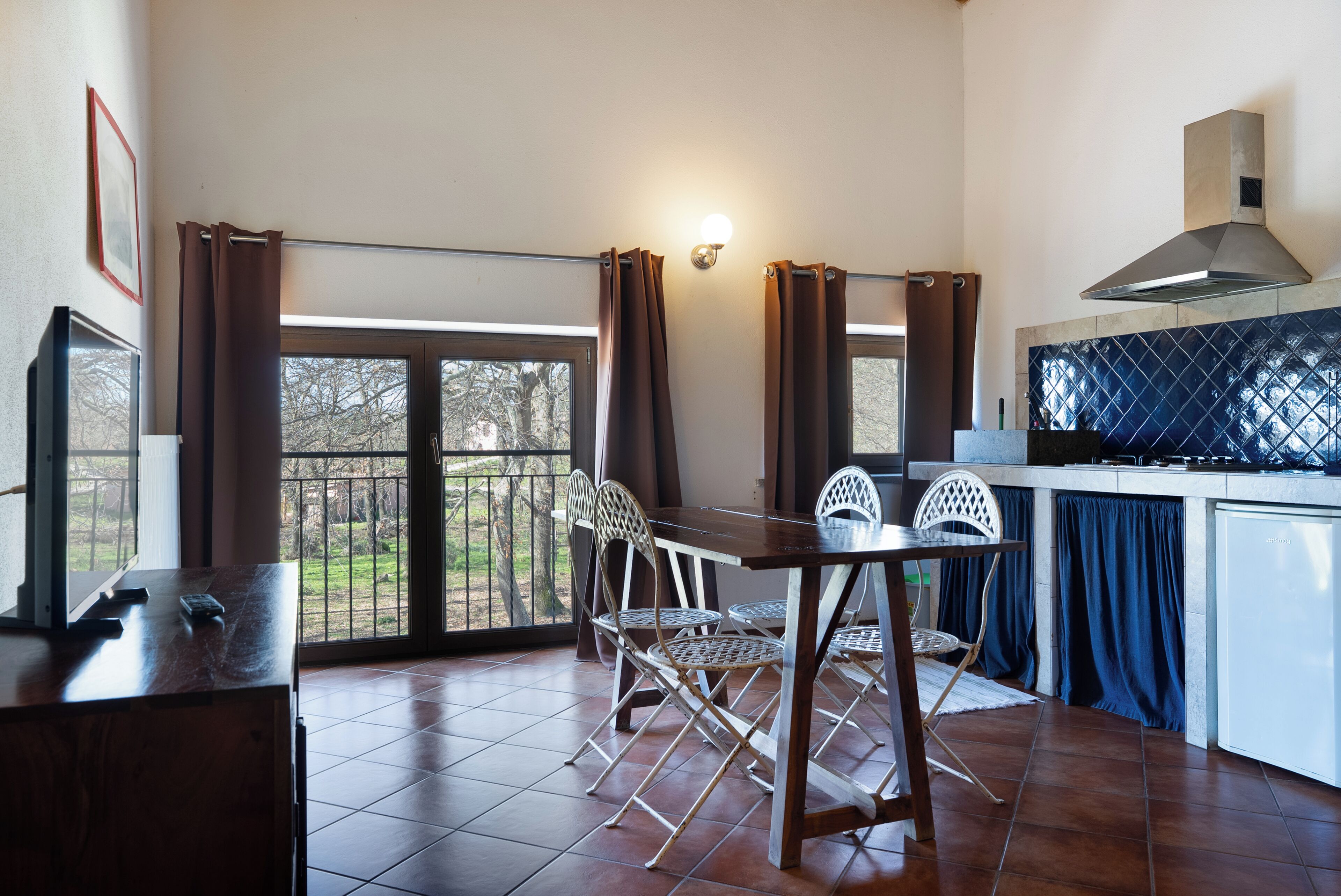Una cocina con comedor, televisor y vista al exterior.