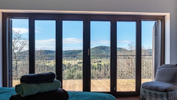 Et værelse med seng, stol og udsigt til en balkon med gelænder.