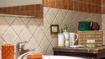 Un baño con salpicadero de azulejos, un lavabo, un espejo y artículos de aseo en la encimera.